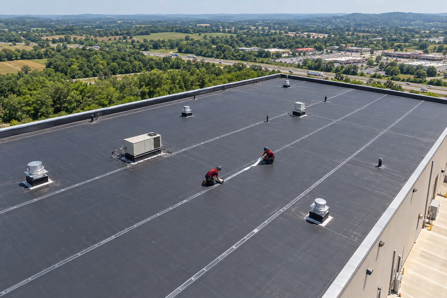 Roofer in a logo uniform rolling a taped seam on a black EPDM rubber roof